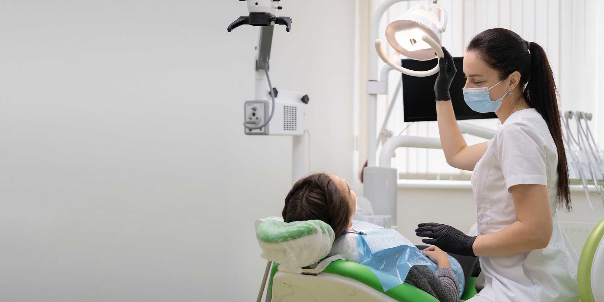 Caucasian woman dentist doctor in office with dental equipment microscope treats teeth to patient in chair.