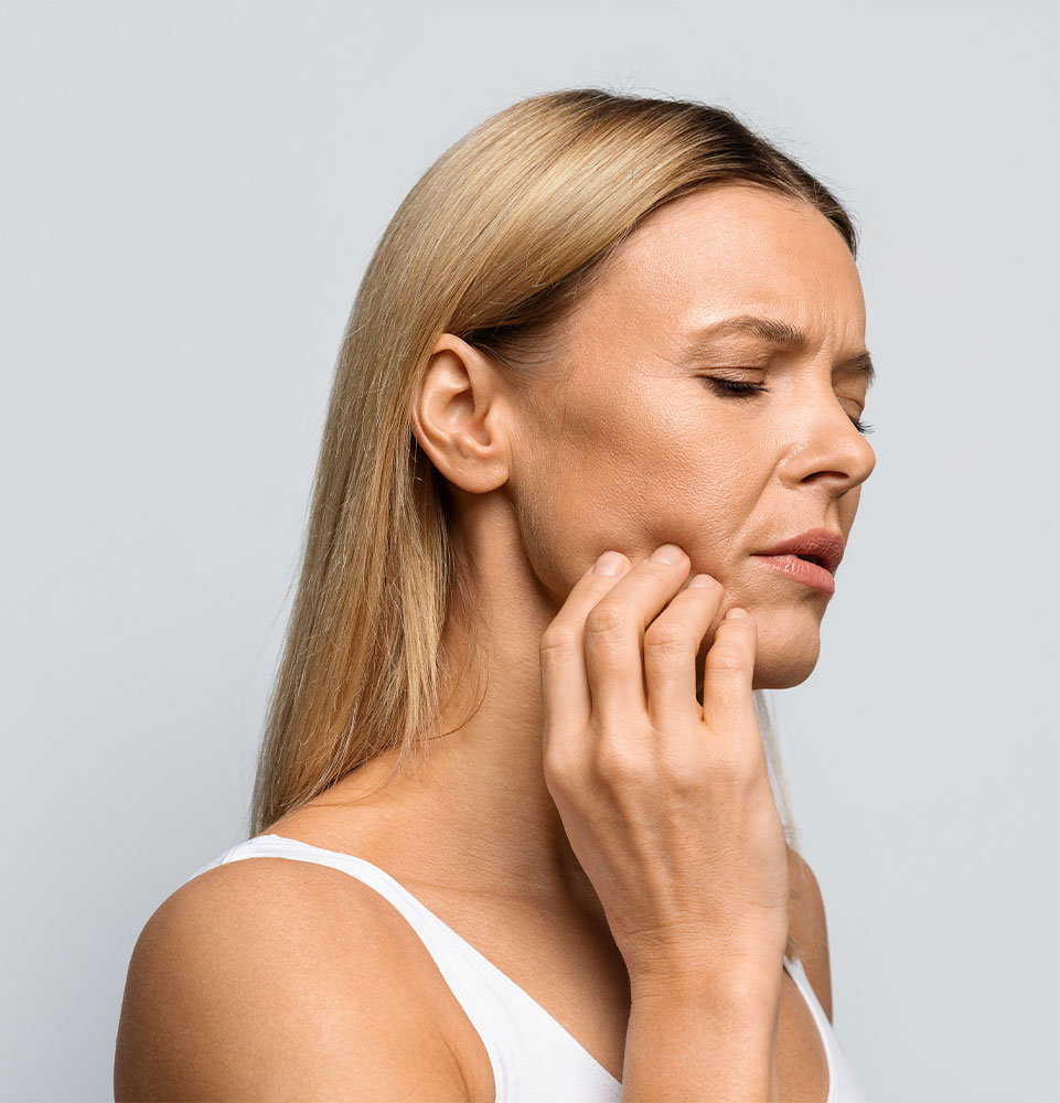 Middle aged woman in pain touching her cheek