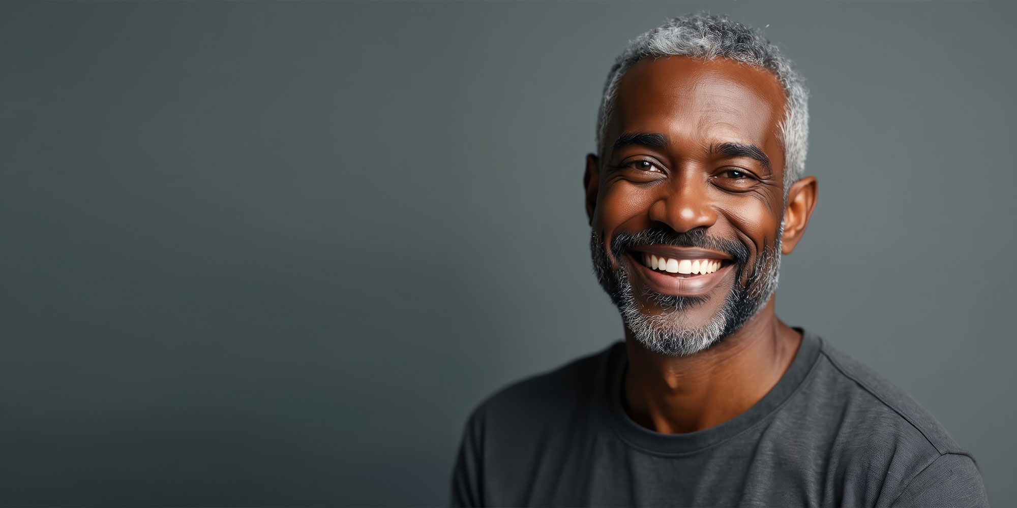 Smiling portrait of middle-aged black man healthy skin, great teeth. Charming, mature model with silver hair embodies dental care