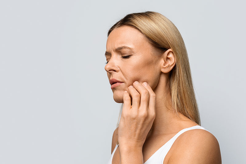 Middle aged woman in pain touching her cheek