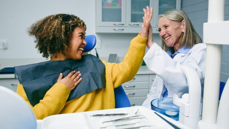 A dentist holding a paycheck, smiling, with a stethoscope around their neck. The text on the image says "Negotiating Your Dental Salary".